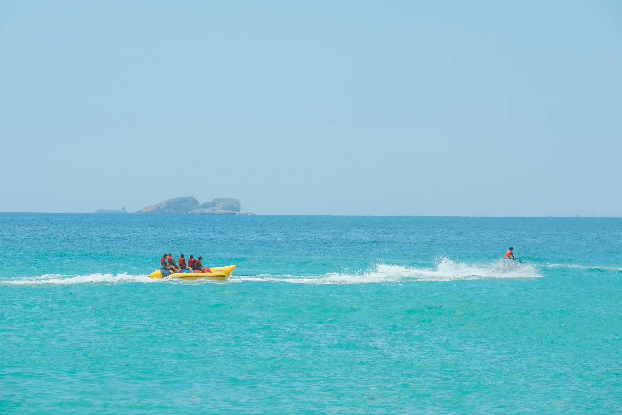 Banana boat sendo puxado por lancha, grupo com colete salva-vidas